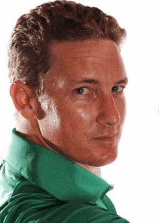 A person with short hair wearing a green collared shirt looks over their shoulder at the camera. The background is plain white.